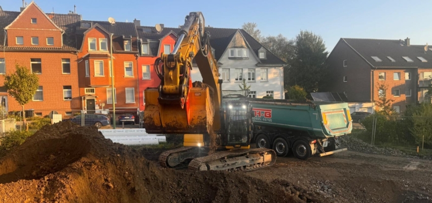 Kettenbagger lädt Erdmaterial in einen Kipper auf einer Baustelle in der Region